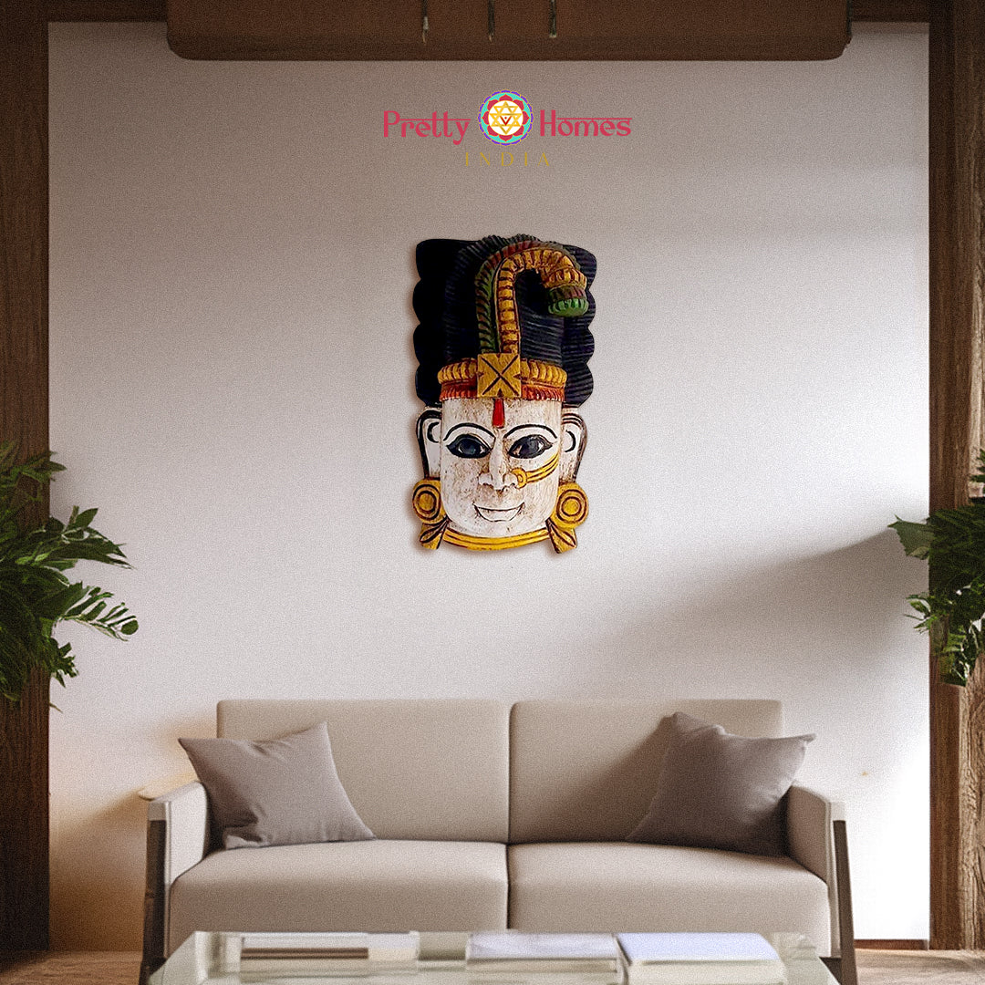 Decorative hand-painted wooden deity head mask with multicolour crown, staged on living room wall.