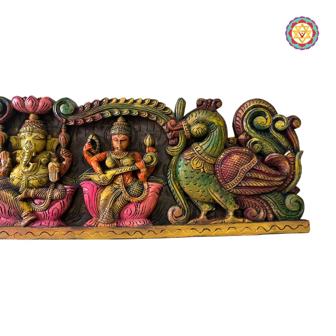 Decorative wall art with colorful figures on a white background: Side view of carved Ganesh, Laxmi & Saraswati wall panel


