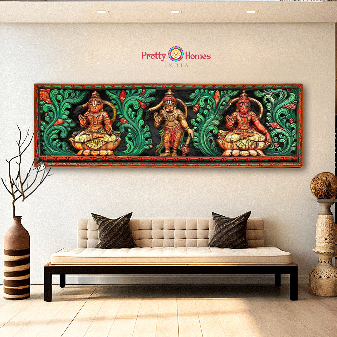 A wood-carved horizontal panel depicting Hanumanji in various life forms, with floral carvings, displayed above a modern sofa in a room with a neutral color scheme.