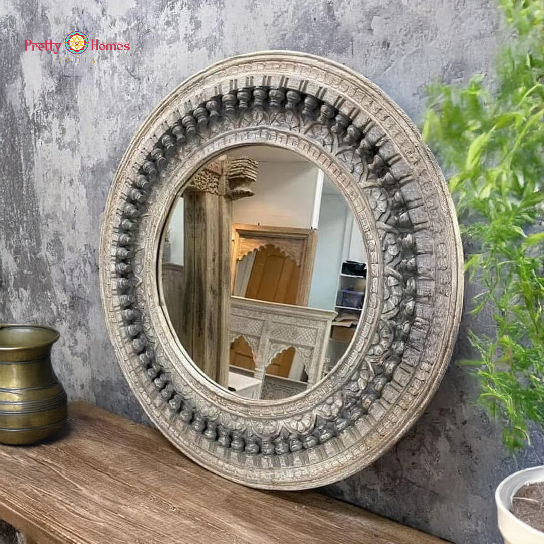 Round carved wooden mirror frame on a rustic tabletop