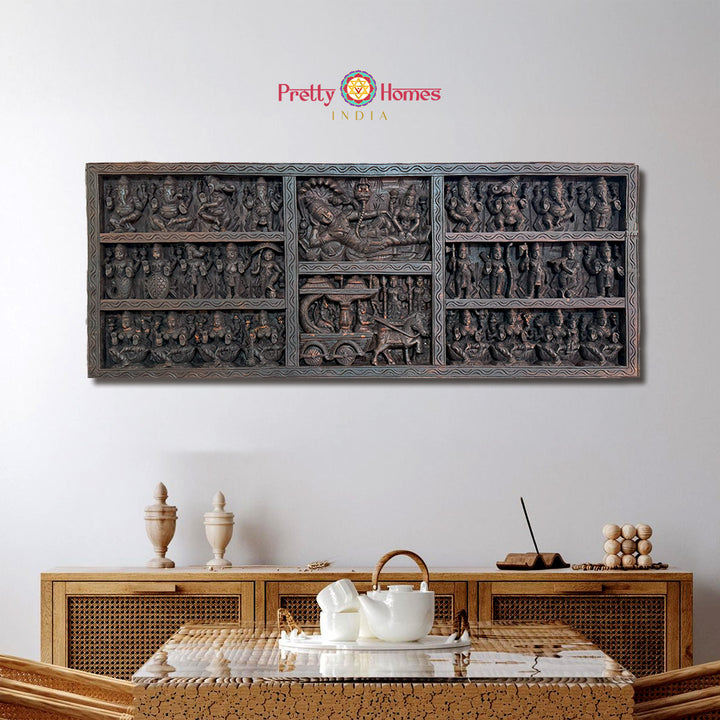 Decorative wall art with intricate carvings above a wooden cabinet and table setup.