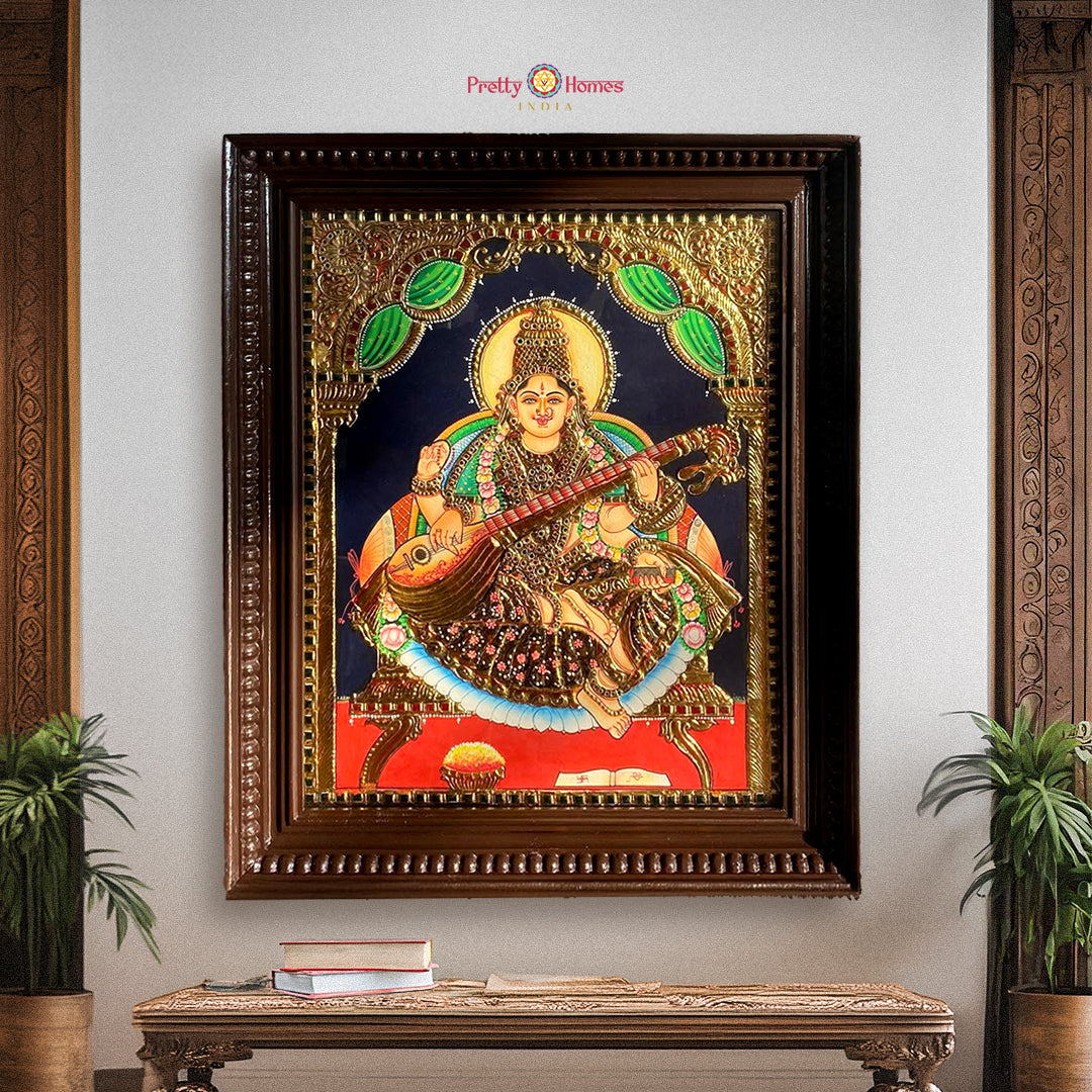 “Framed Saraswati Tanjore painting in 22-carat gold foil displayed on interior wall with traditional decor”