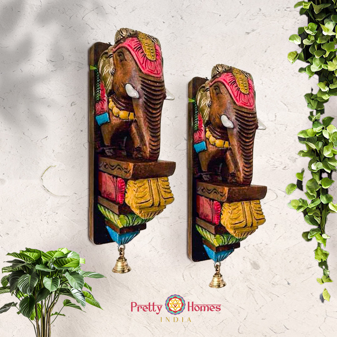Set of two hand-painted wooden elephant wall brackets with bright accents and dangling bells.