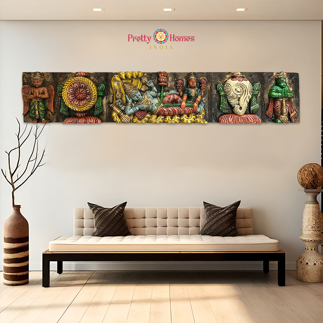 Handcarved wooden wall panel depicting Hindu deity Tirupati Balaji with symbols and floral carvings, displayed on a wall above a sofa.
