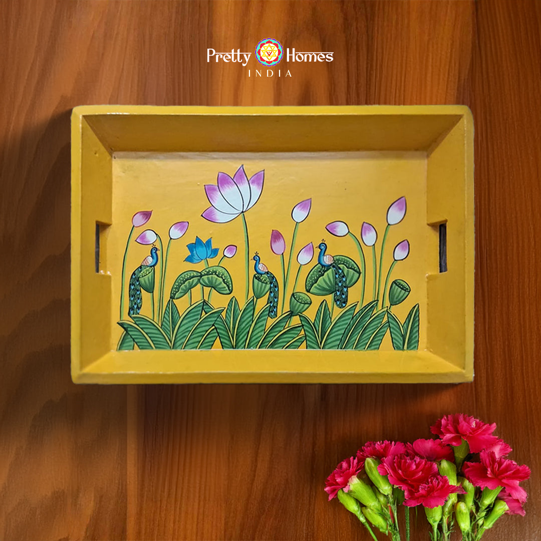 Hand-painted yellow Pichwai serving tray with lotus flowers, displayed on wood.