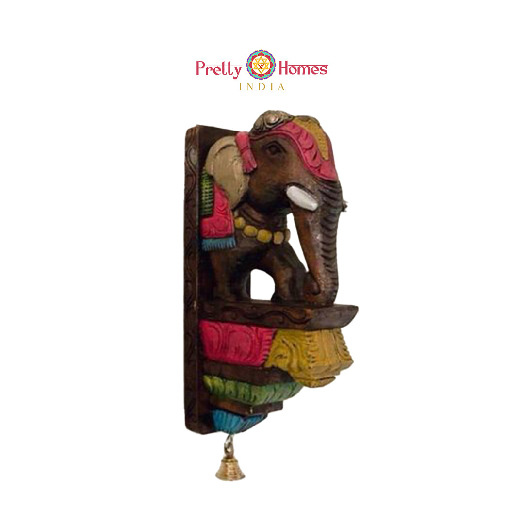 Front-side view of painted wooden elephant wall bracket with colorful carved panels and small bell.