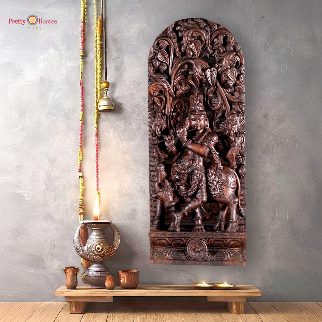 Wooden sculpture of Lord Krishna standing under a canopy with cow
