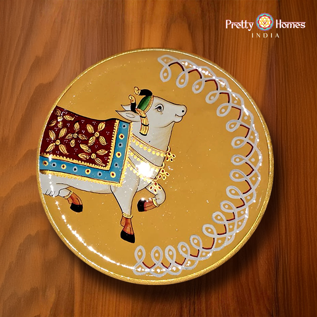 Hand-painted round plate with white ceremonial cow on mustard background