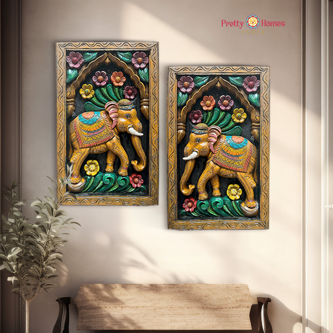 Two vertical wooden wall hangings featuring carved elephants and floral designs, with one panel slightly overlapping the other.