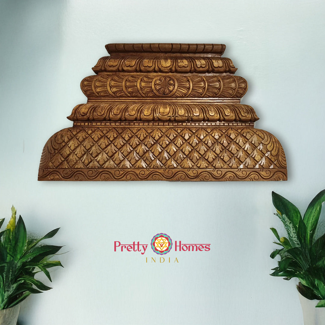 Decorative wooden wall piece with intricate carvings on a white wall, branded 'Pretty Homes India'. Carved wooden gopuram-style panel with traditional architecture design

