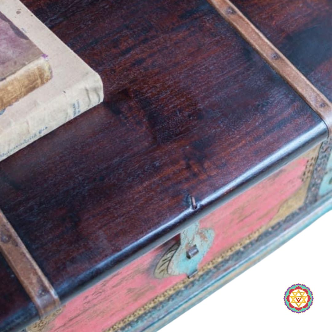 Close-up of brass inlay on wooden trunk — traditional design with gold tone, vintage red-blue painted surface