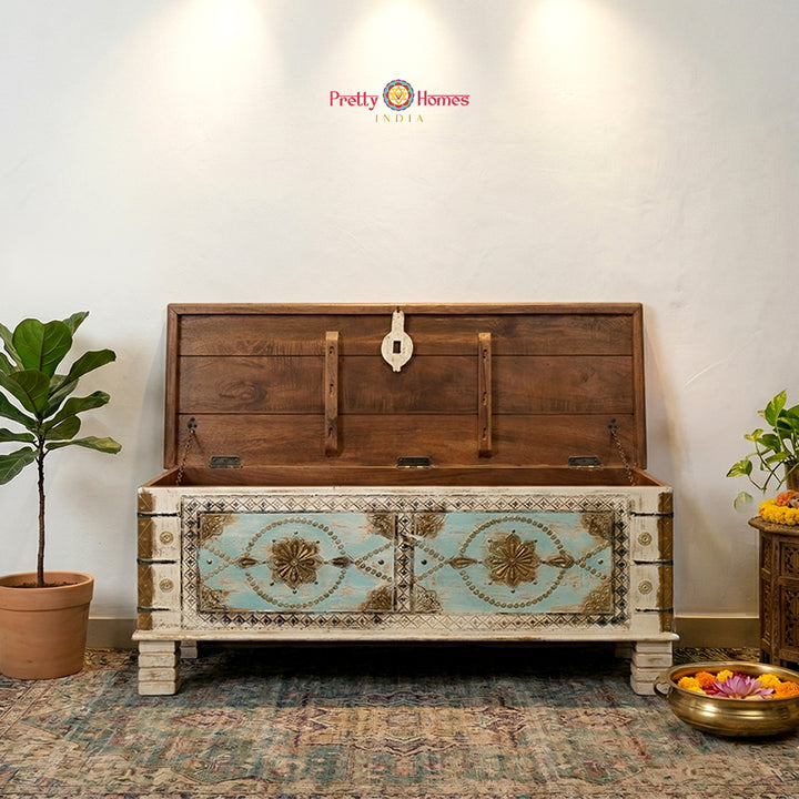 A horizontal hand-carved solid wood trunk table featuring traditional antique brass detailing.